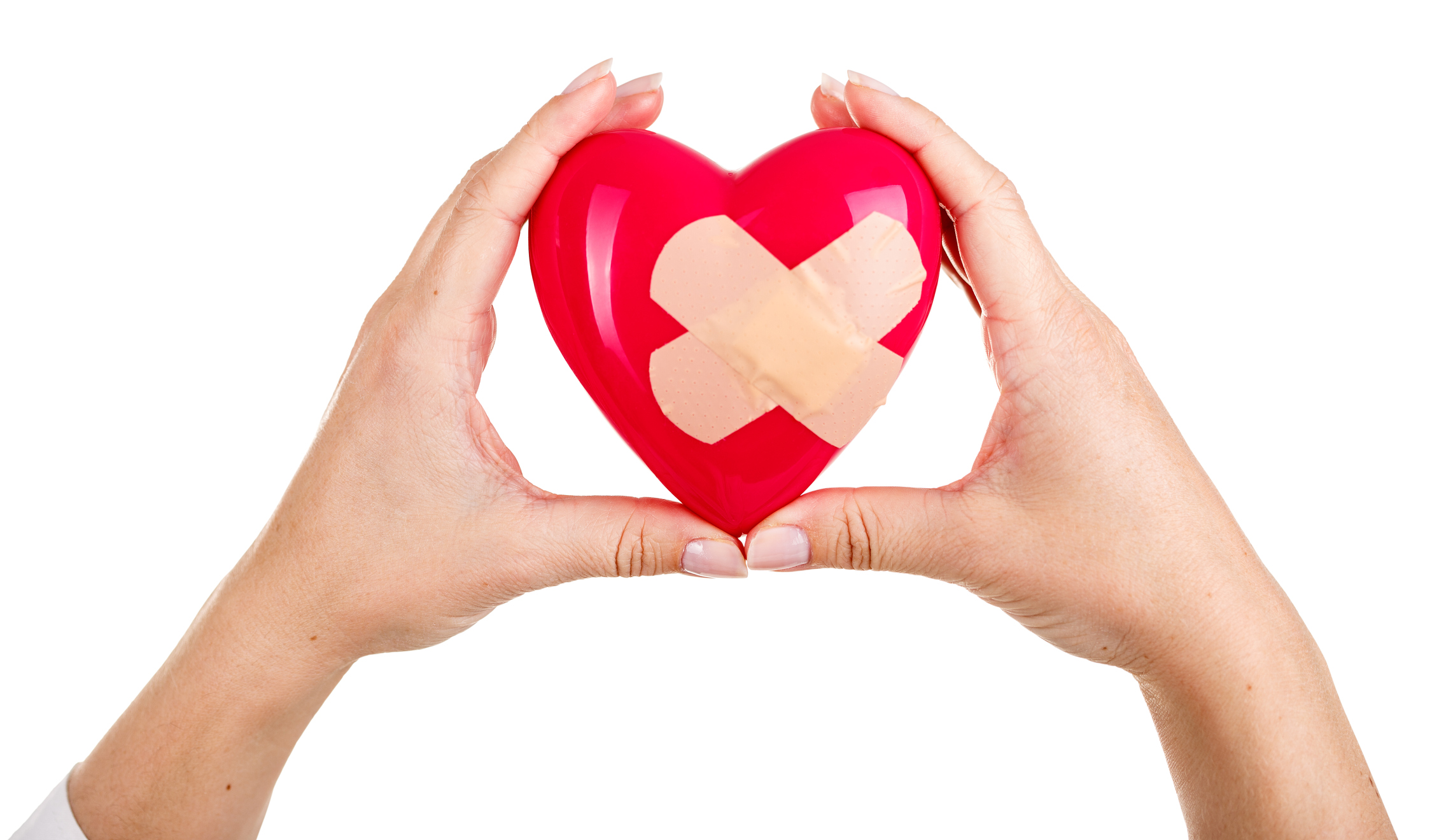 Female hands raised up holding red toy mended heart isolated on white background. Medical help or insurance concept. Cardiology care and health. Heart surgery and resuscitation concept